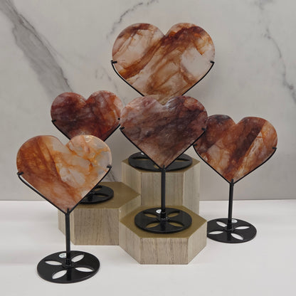 Collection of Fire Quartz hearts black stands, shown against a white wall and marble-patterned background.