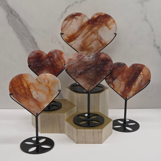 Collection of Fire Quartz hearts black stands, shown against a white wall and marble-patterned background.