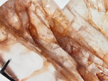 A close-up of a polished stone slab with natural brown and cream marbling and crystalline texture, with a small black object visible in the lower-left corner.