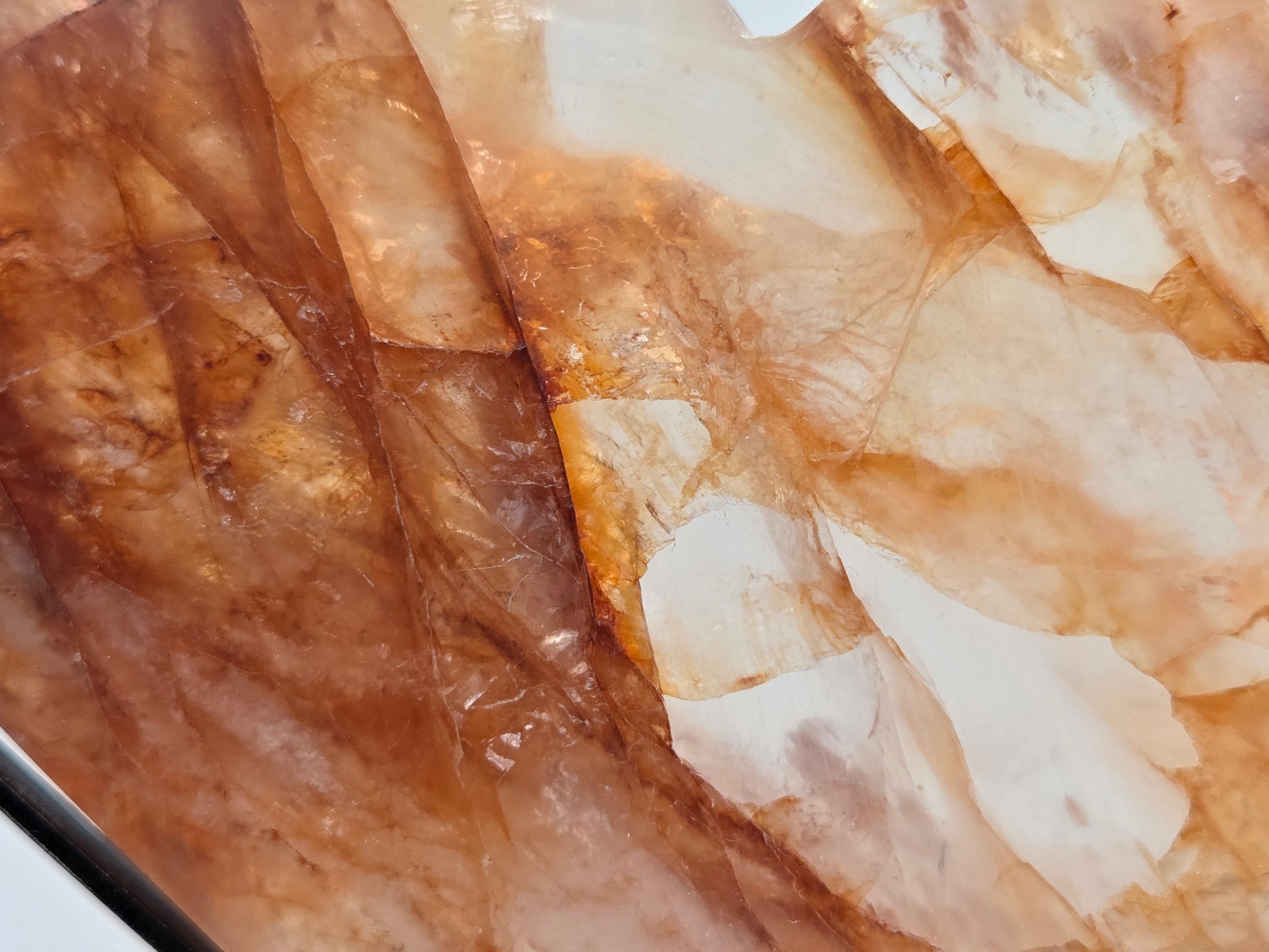 A close-up of a polished stone slab with natural marbled patterns in warm brown, tan, cream, and translucent beige tones.