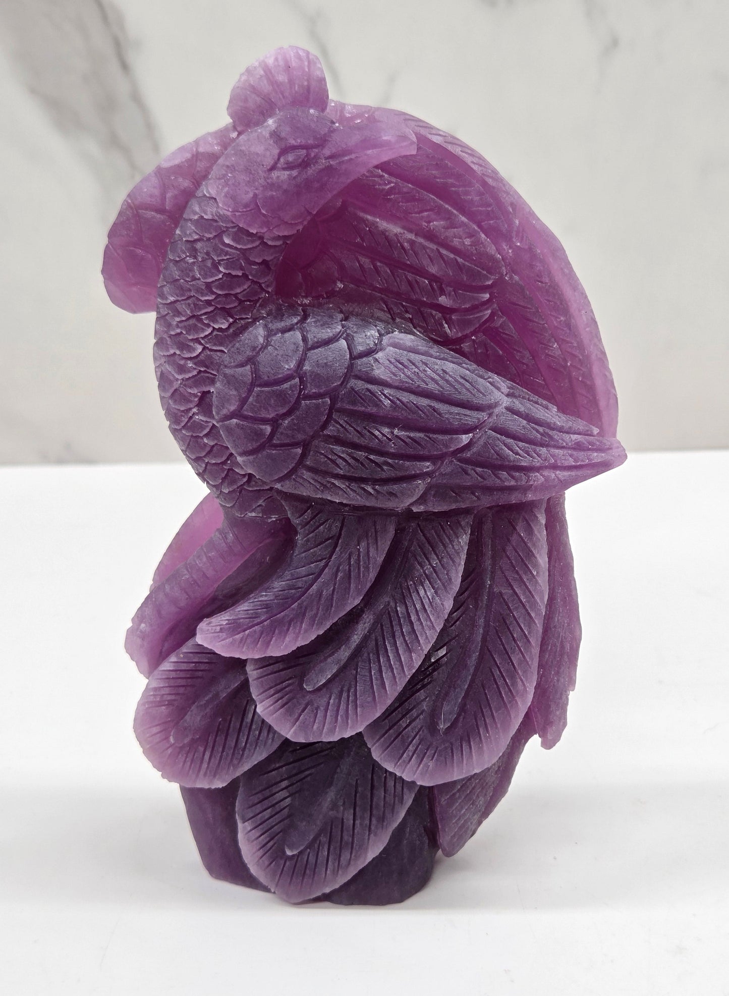 Purple lepidolite phoenix carving on a white background