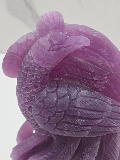 Close up of a purple lepidolite phoenix carving on a white background