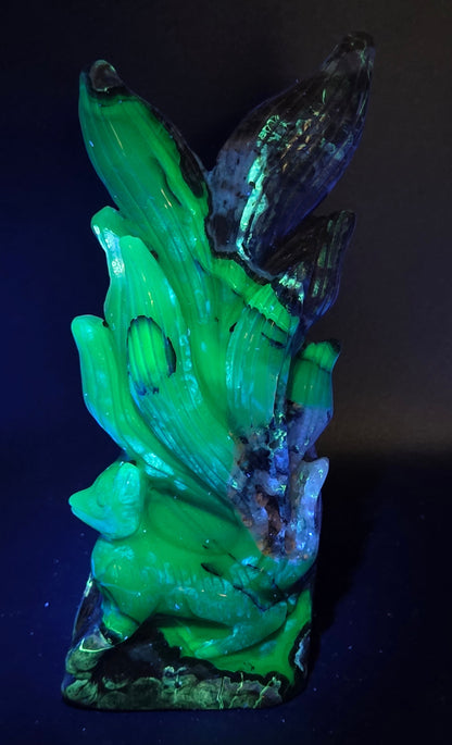 Volcano Agate carving of a nine tail fox under UV light against a black background