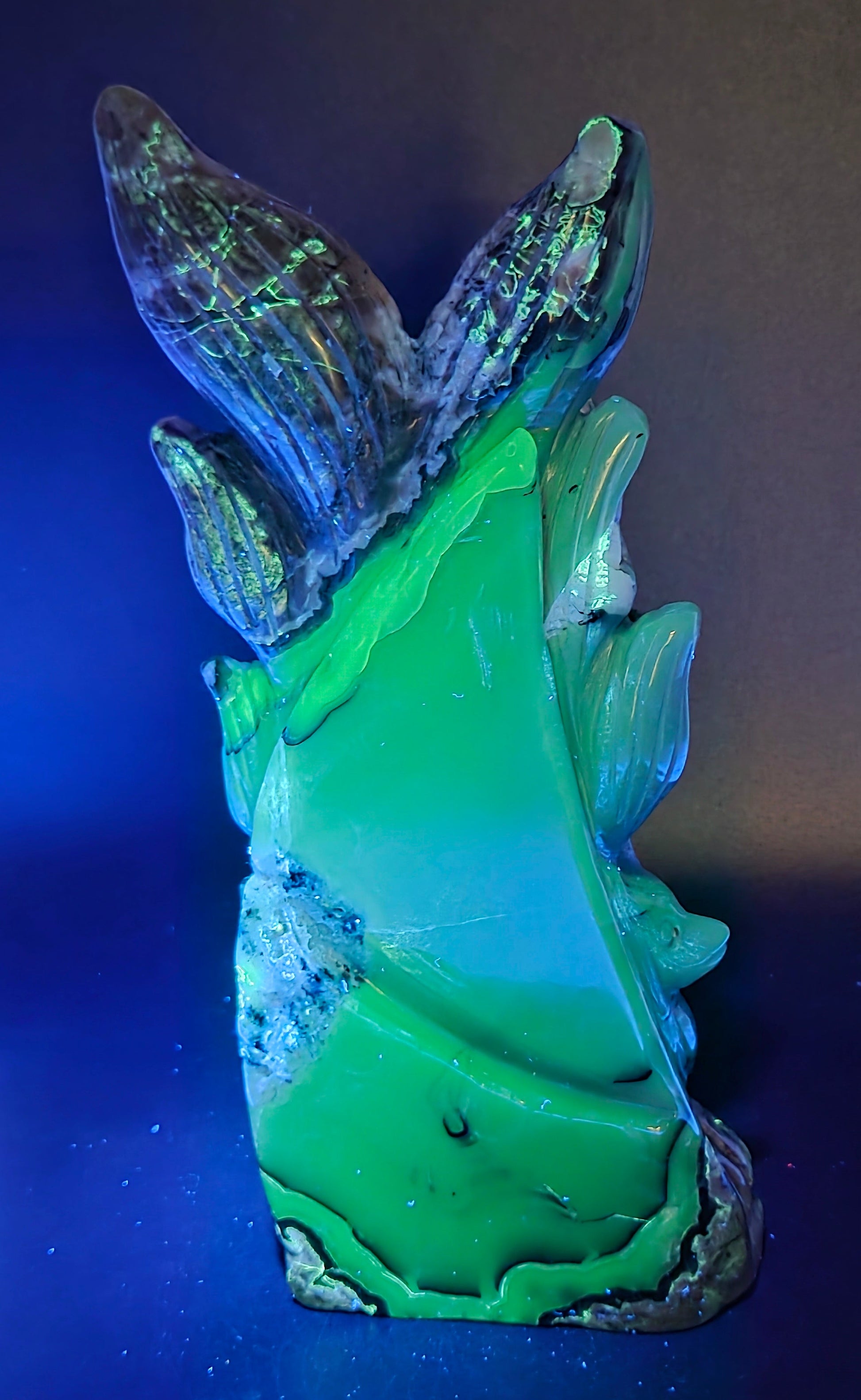 Volcano Agate carving of a nine tail fox under UV light against a black background