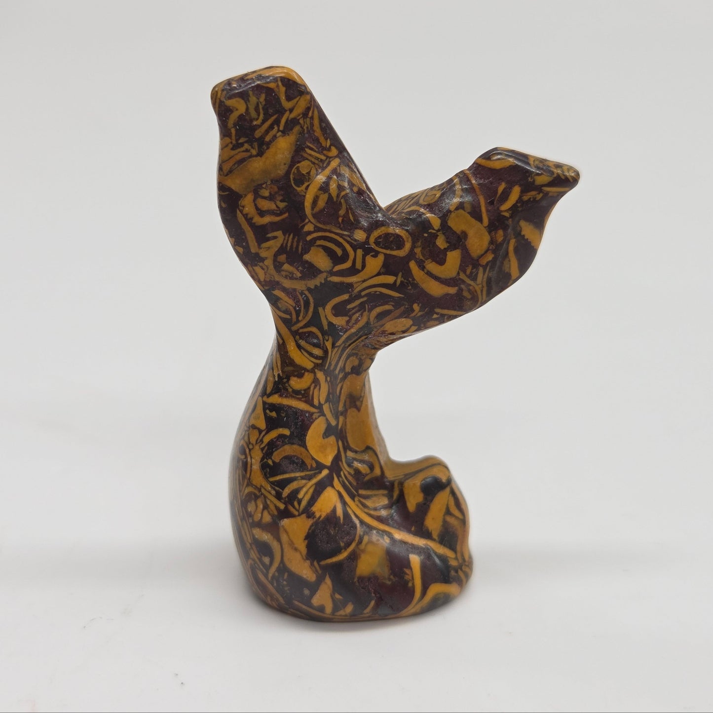 A small carved stone figurine shaped like a mermaid tail, made from calligraphy stone, photographed against a plain light background.