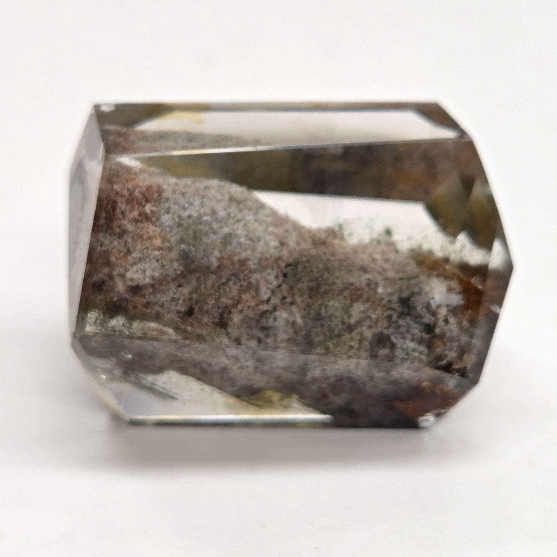 A faceted clear crystal gemstone with a prominent brown and gray textured inlay or matrix inside, shown on a plain white background.