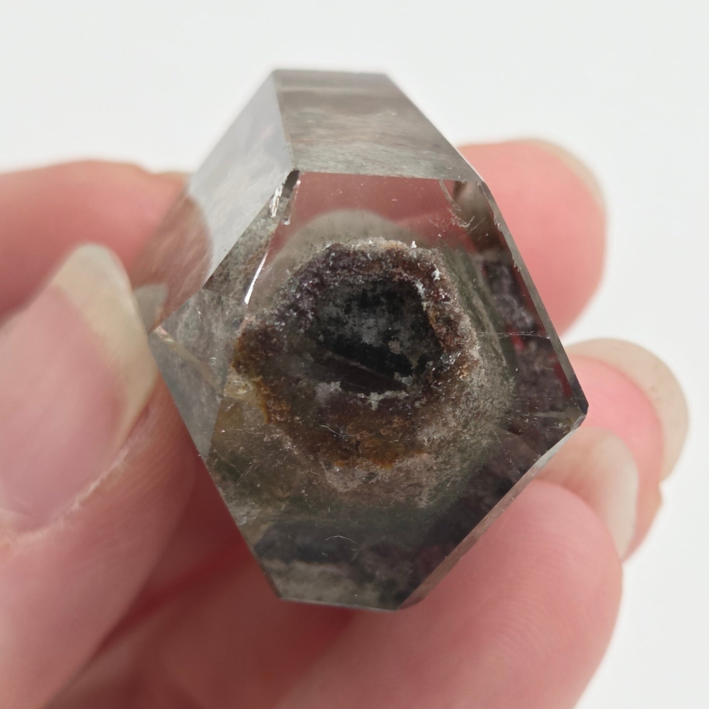 A clear faceted crystal ring held between fingers against a plain white background.