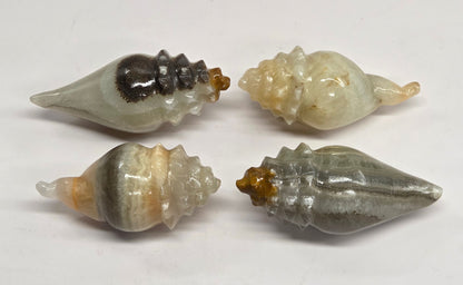 Four polished stone seashell-shaped ornaments arranged in a 2x2 grid on a plain white background.