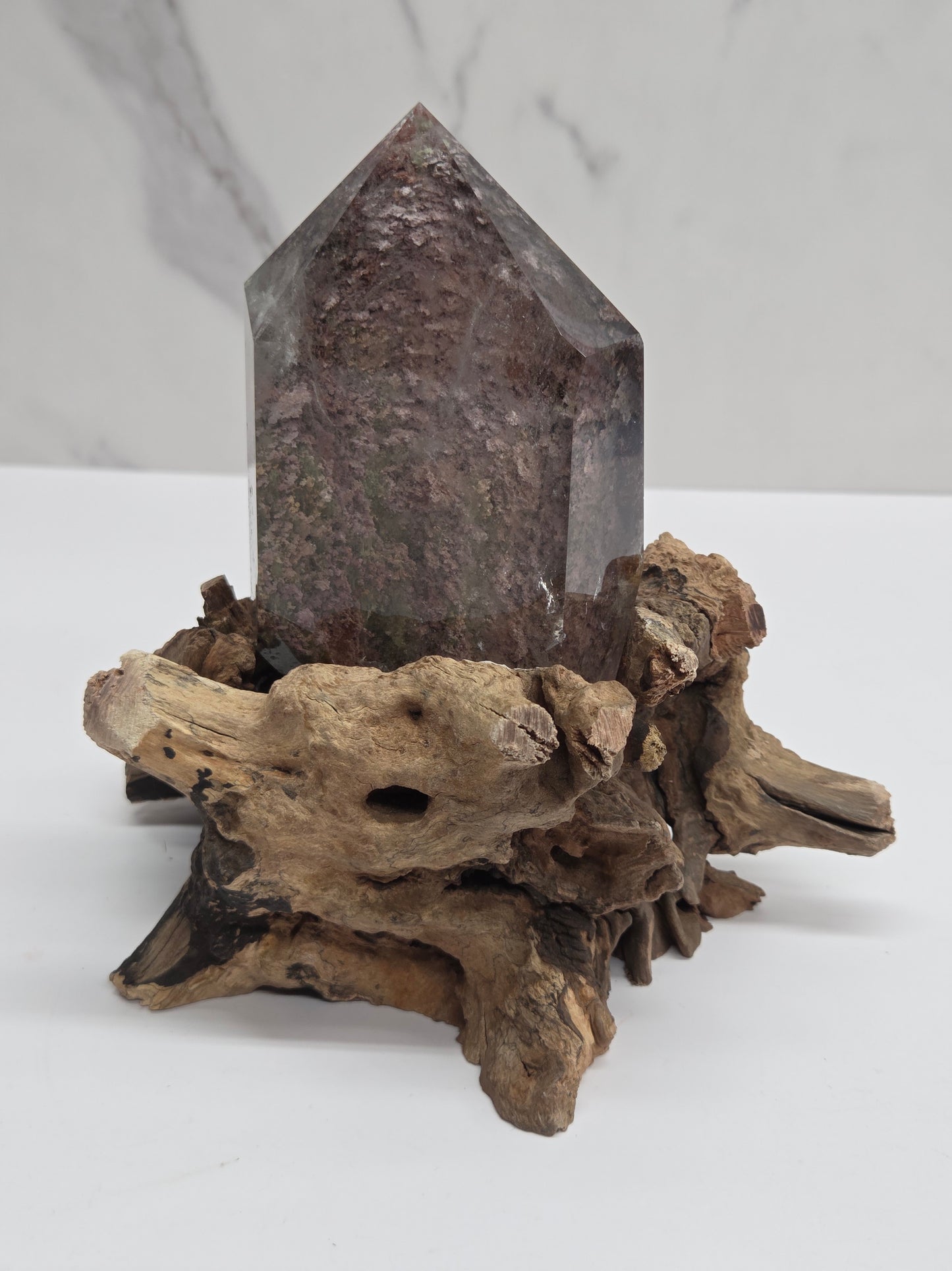 A natural driftwood crystal mount featuring a pointed gray quartz crystal attached to a textured, weathered piece of wood, displayed against a clean white background.