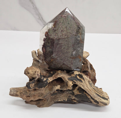 A natural clear quartz crystal point mounted on a piece of weathered driftwood, displayed against a clean white background.