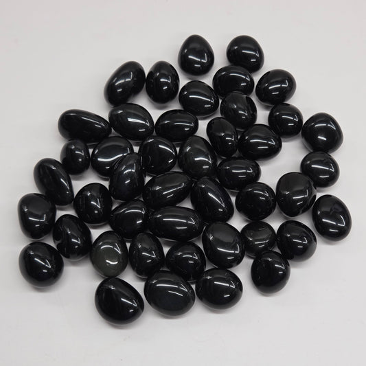 Polished osidian tumble stones on a white surface