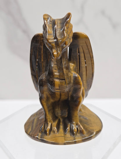 A small carved wooden dragon figurine with a glossy finish, mounted on a clear acrylic stand against a white marble-textured background.