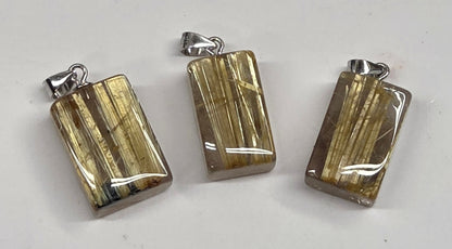 Three polished rectangular pendants with silver-toned bail loops, featuring a metallic gold and silver striped pattern, displayed on a light gray surface.