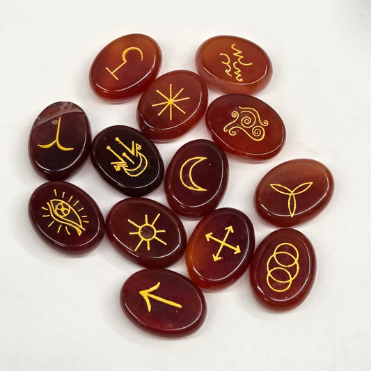 A set of ten polished reddish-brown gemstone tumbled stones, each engraved with a different yellow symbol, arranged on a plain white surface.