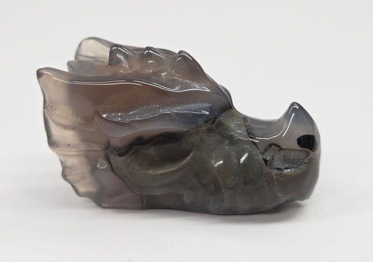 A small carved stone object with a smooth, polished finish, featuring a dark gray and translucent smoky appearance, photographed on a plain light background.