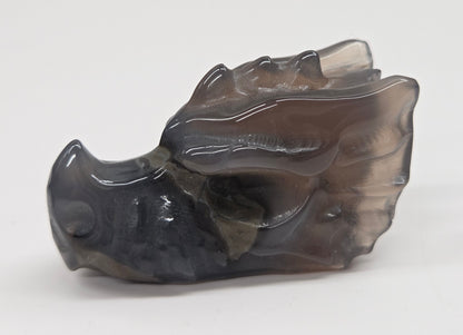 A carved translucent dark gray stone object with organic marbled patterns, photographed on a plain light gray background.