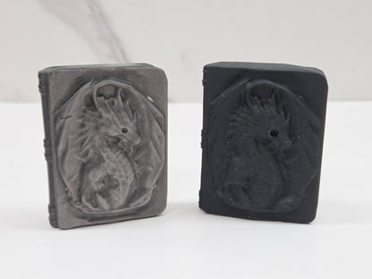 Two rectangular obsidian carvings with embossed dragon designs, displayed side by side on a white surface against a light gray background.