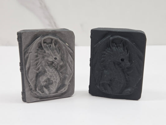 Two rectangular obsidian carvings with embossed dragon designs, displayed side by side on a white surface against a light gray background.