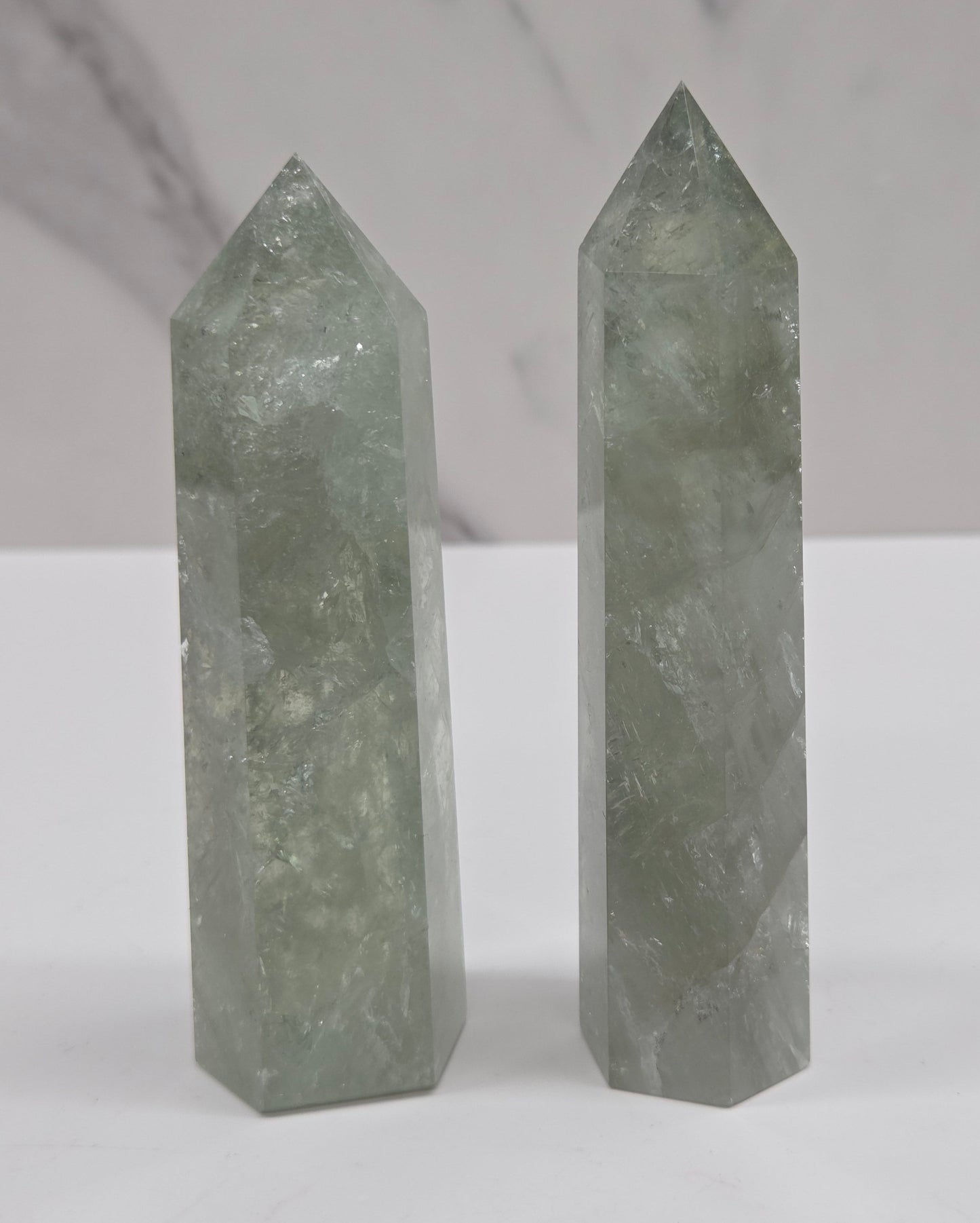 Two green crystal point towers displayed vertically against a white background.