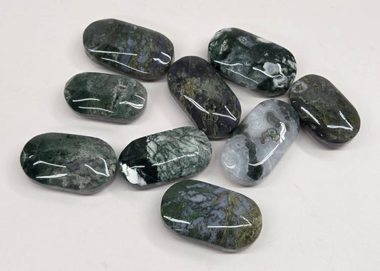 A group of nine polished dark green and gray tumbled stone beads with natural marbled patterns, arranged on a plain white surface.