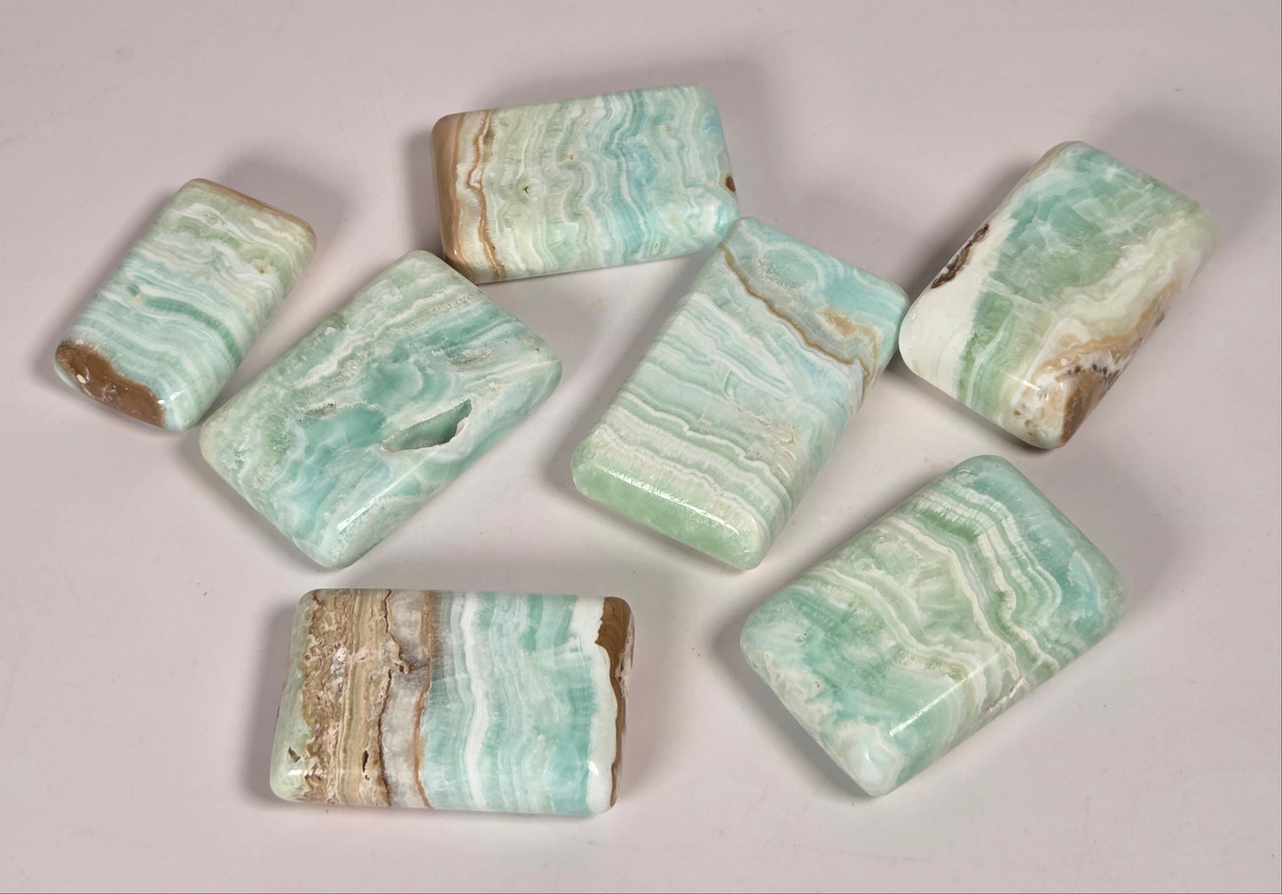 Banded calcite crystals carved into the shape of a soap bar with blue, green and brown coloring on a white background