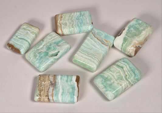 Banded calcite crystals carved into the shape of a soap bar with blue, green and brown coloring on a white background