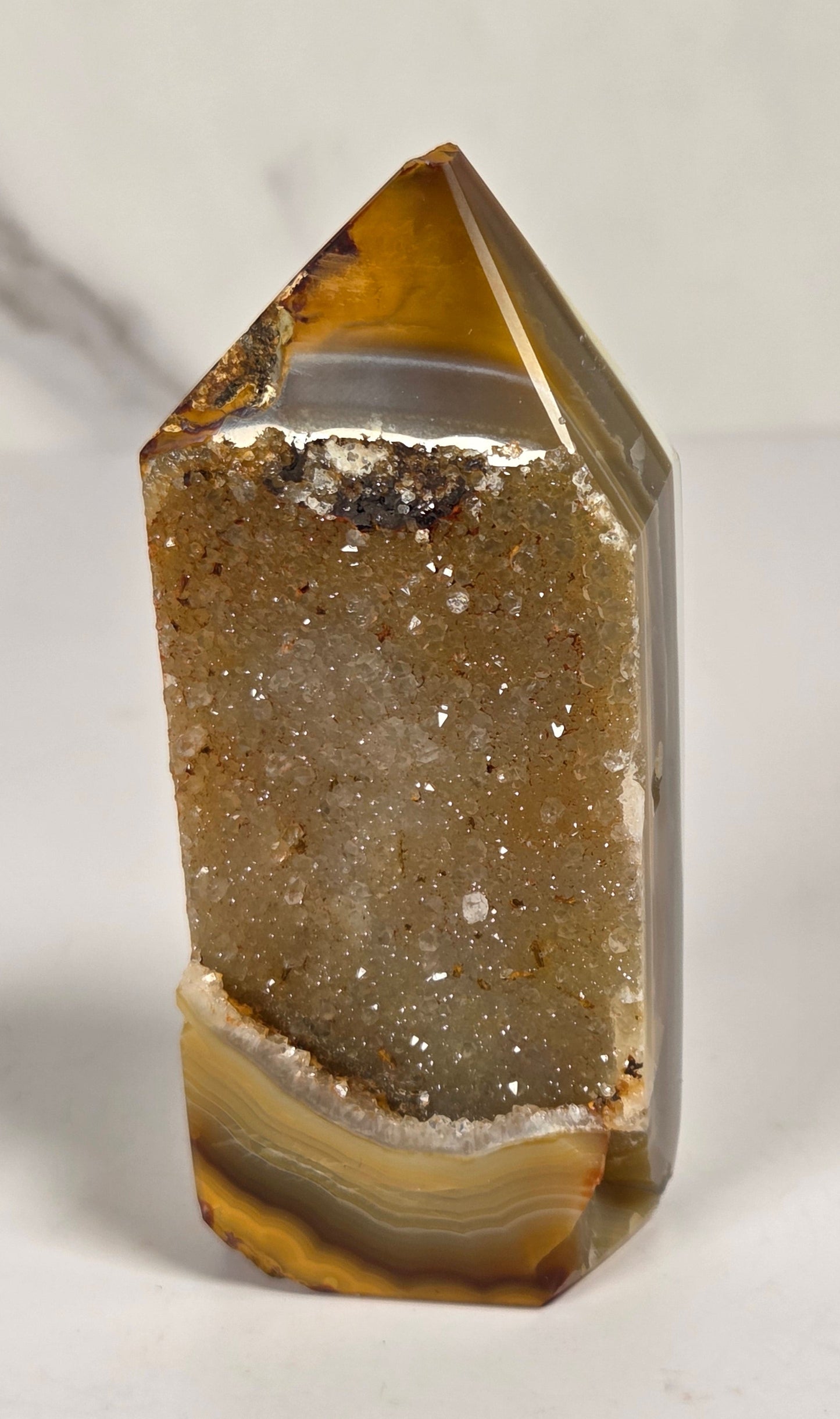 Agate point with brown coloring and druzy quartz on a white background