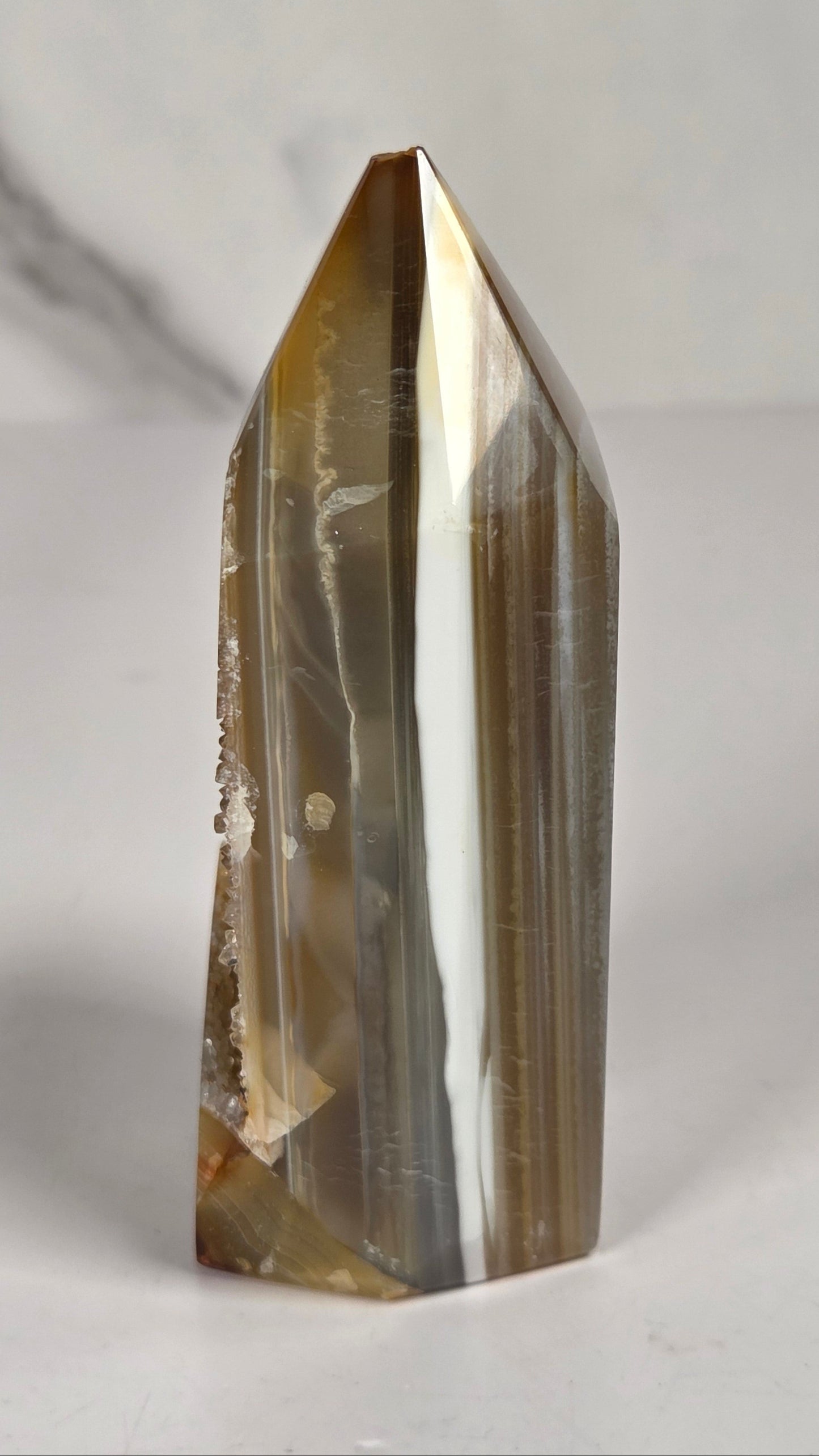 Agate point with brown coloring and druzy quartz on a white background