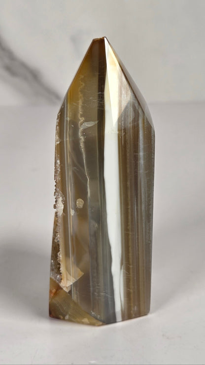 Agate point with brown coloring and druzy quartz on a white background