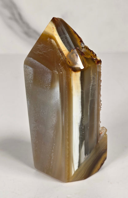 Agate point with brown coloring and druzy quartz on a white background