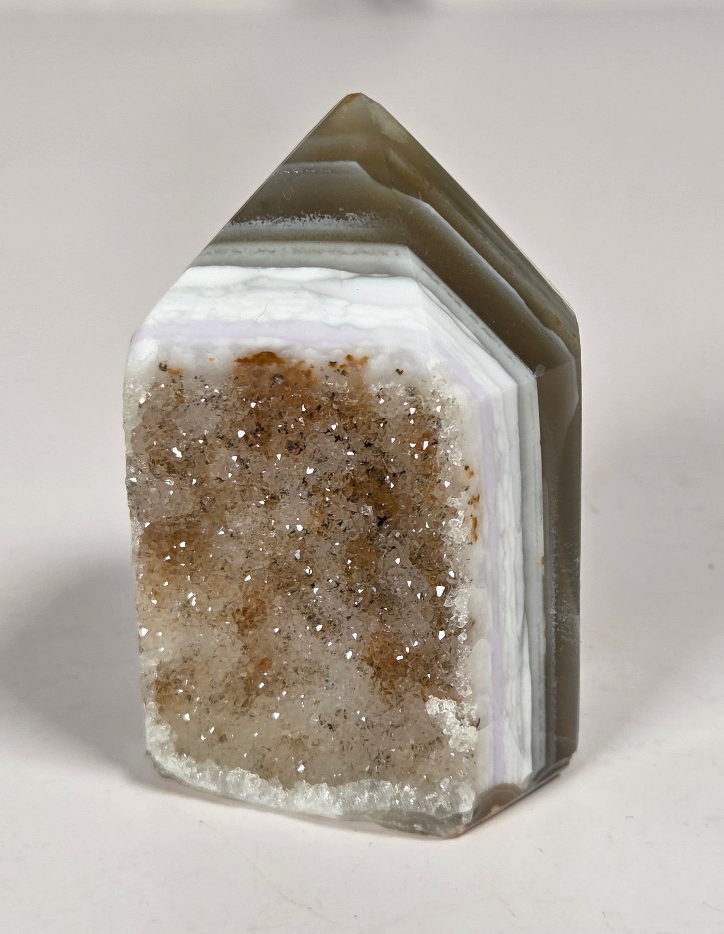 Agate point with brown coloring and druzy quartz on a white background