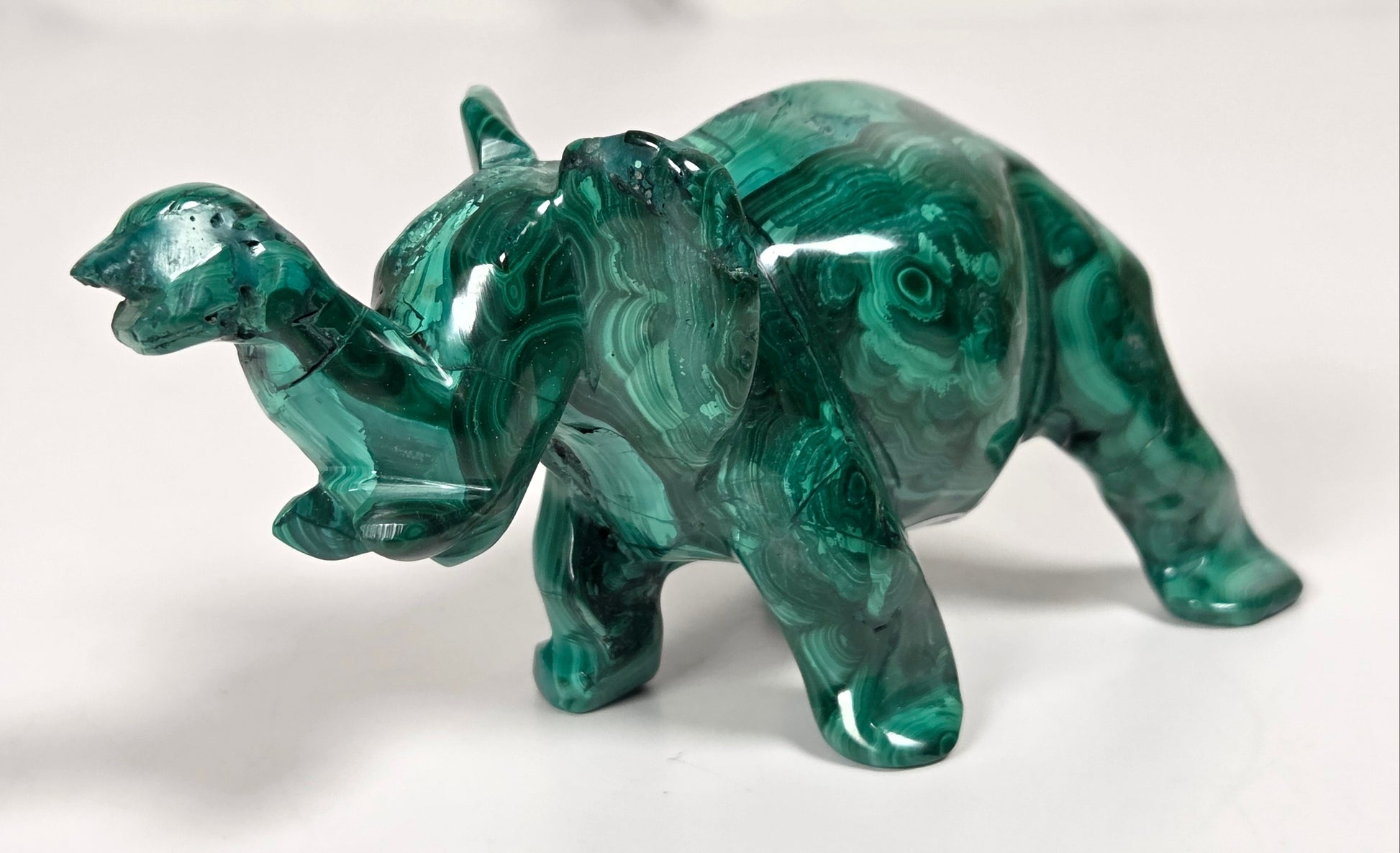 Green malachite crystal carved into the shape of an elephant against a white background