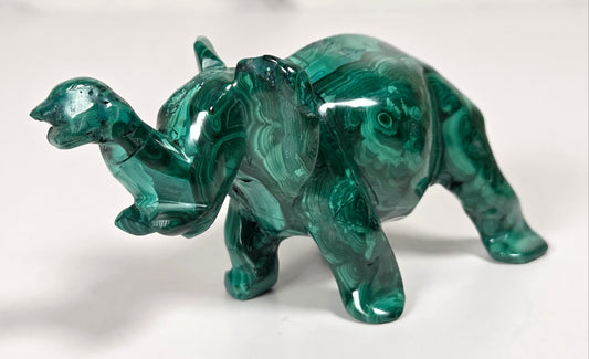 Green malachite crystal carved into the shape of an elephant against a white background