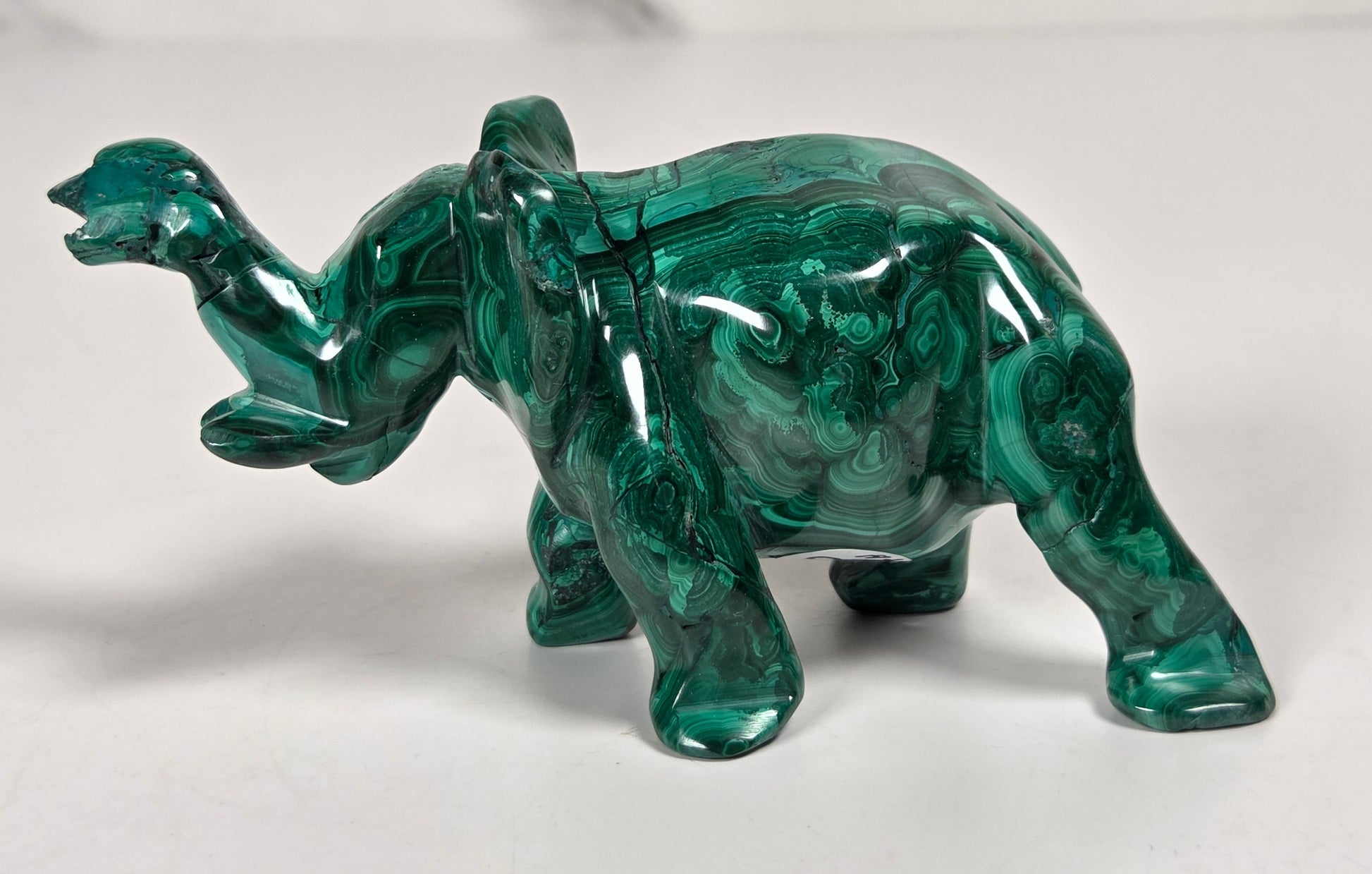 Green malachite crystal carved into the shape of an elephant against a white background