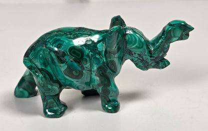 Green malachite crystal carved into the shape of an elephant against a white background