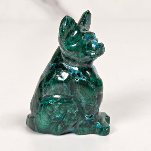 Green malachite crystal carved into the shape of a cat against a white background