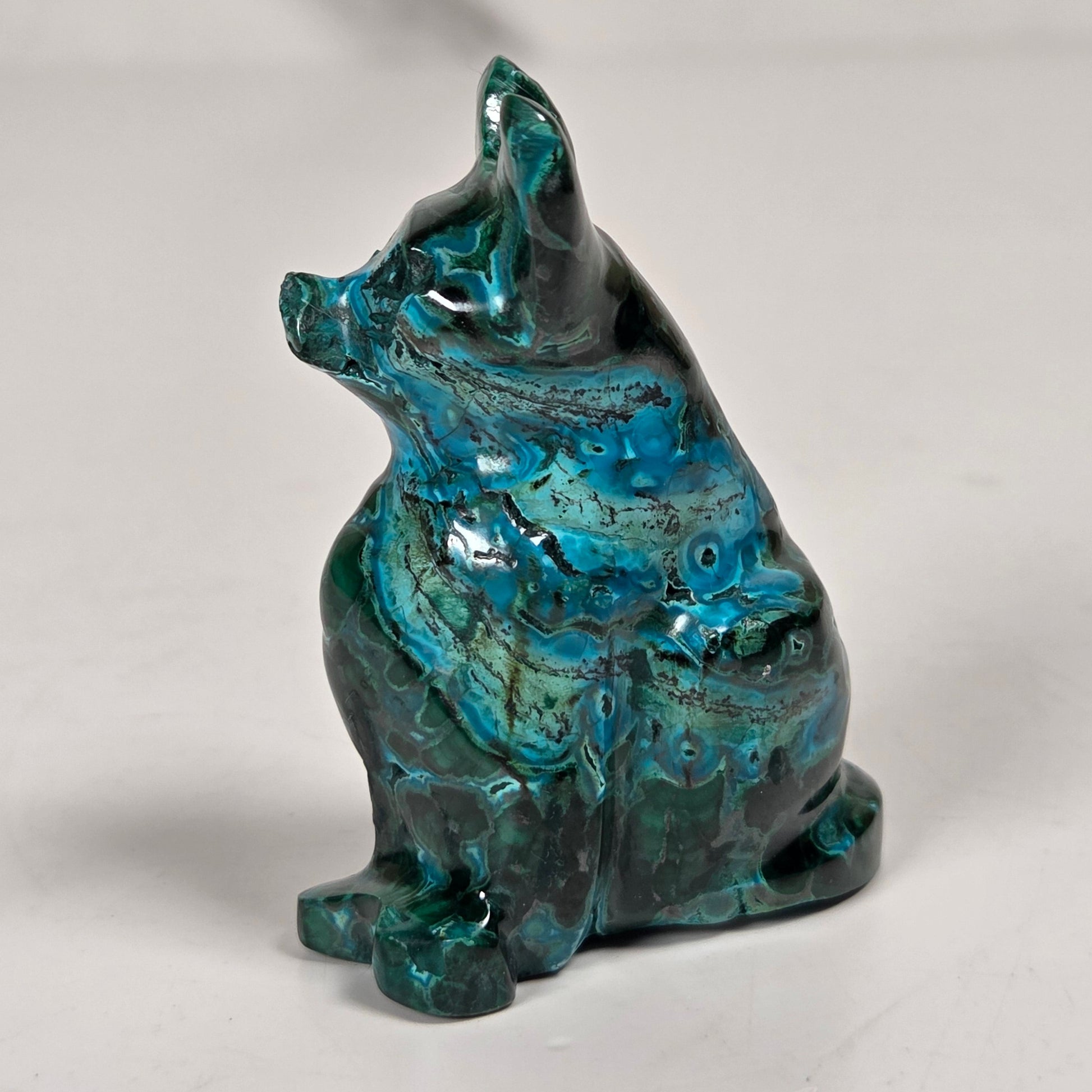 Green malachite crystal carved into the shape of a cat against a white background