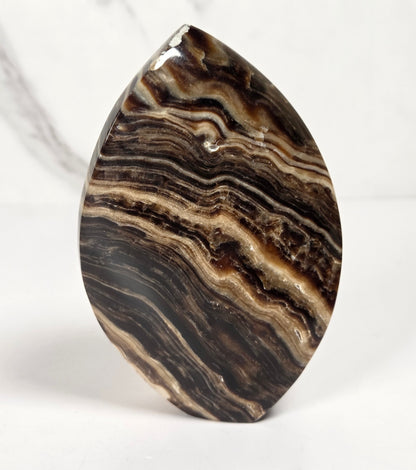 Banded chocolate calcite flame with brown and tan coloring on a white background