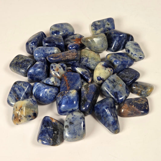 A pile of polished blue tumbled stones with white and gray veining, arranged on a plain off-white background.