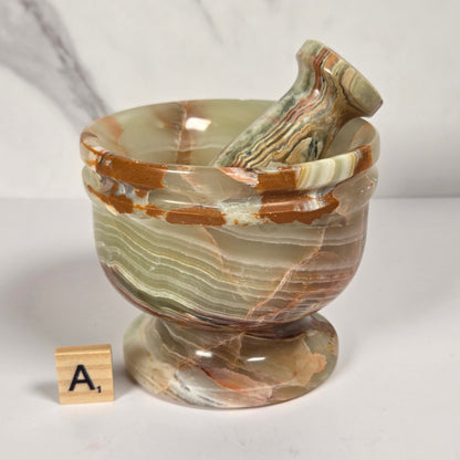 Afghan Onyx pestle and mortar set on a white surface with a gray background