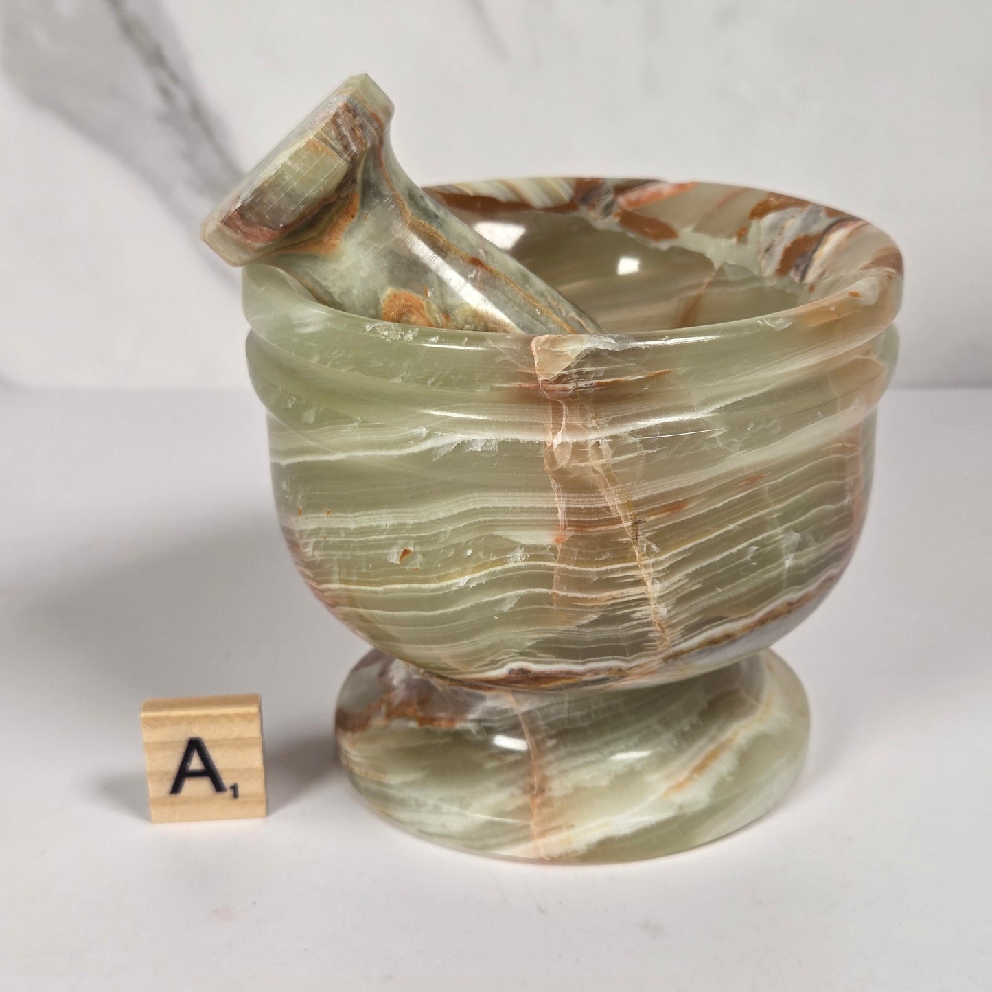 Afghan Onyx pestle and mortar set on a white surface with a gray background