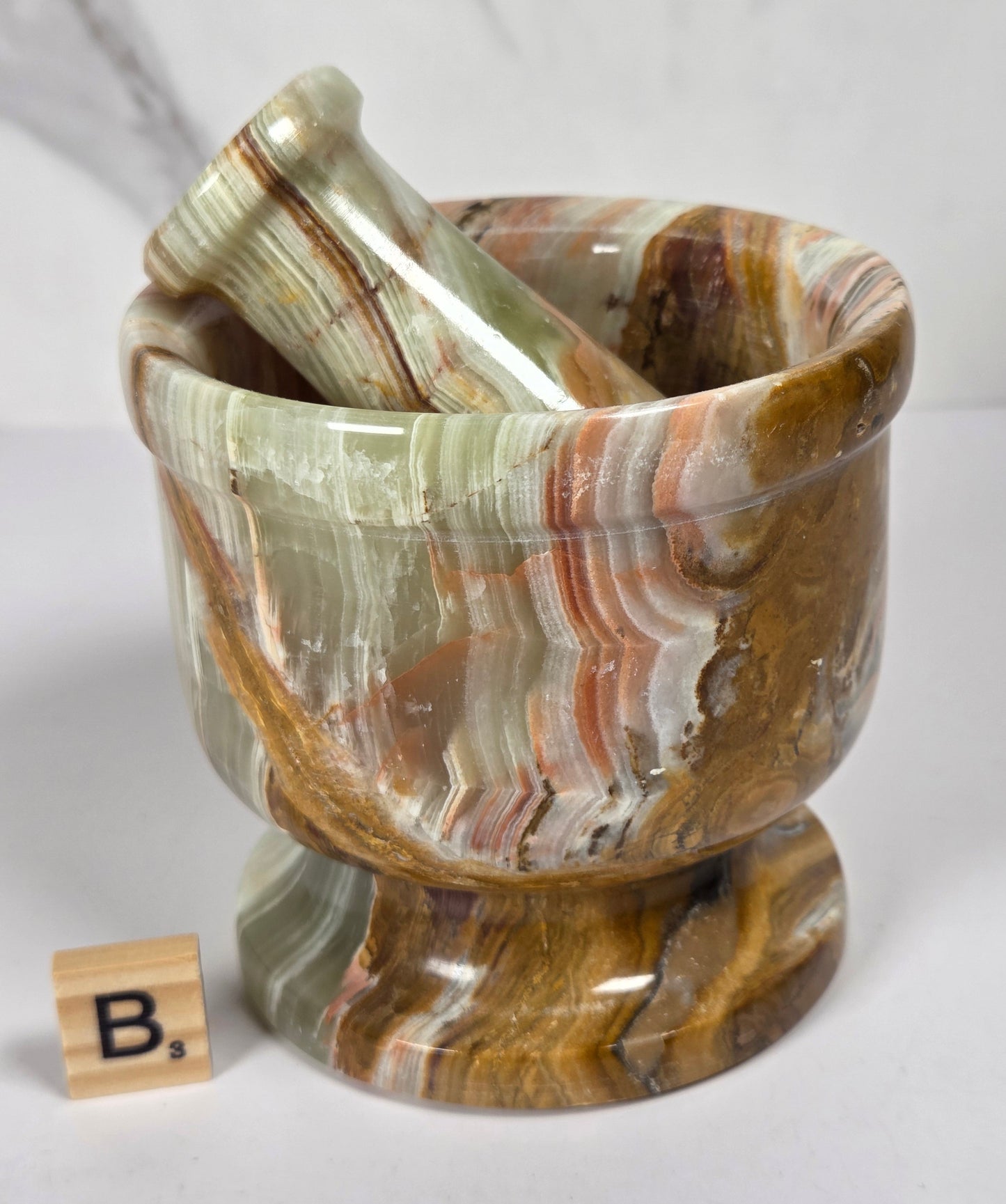 Afghan Onyx pestle and mortar set on a white surface with a gray background