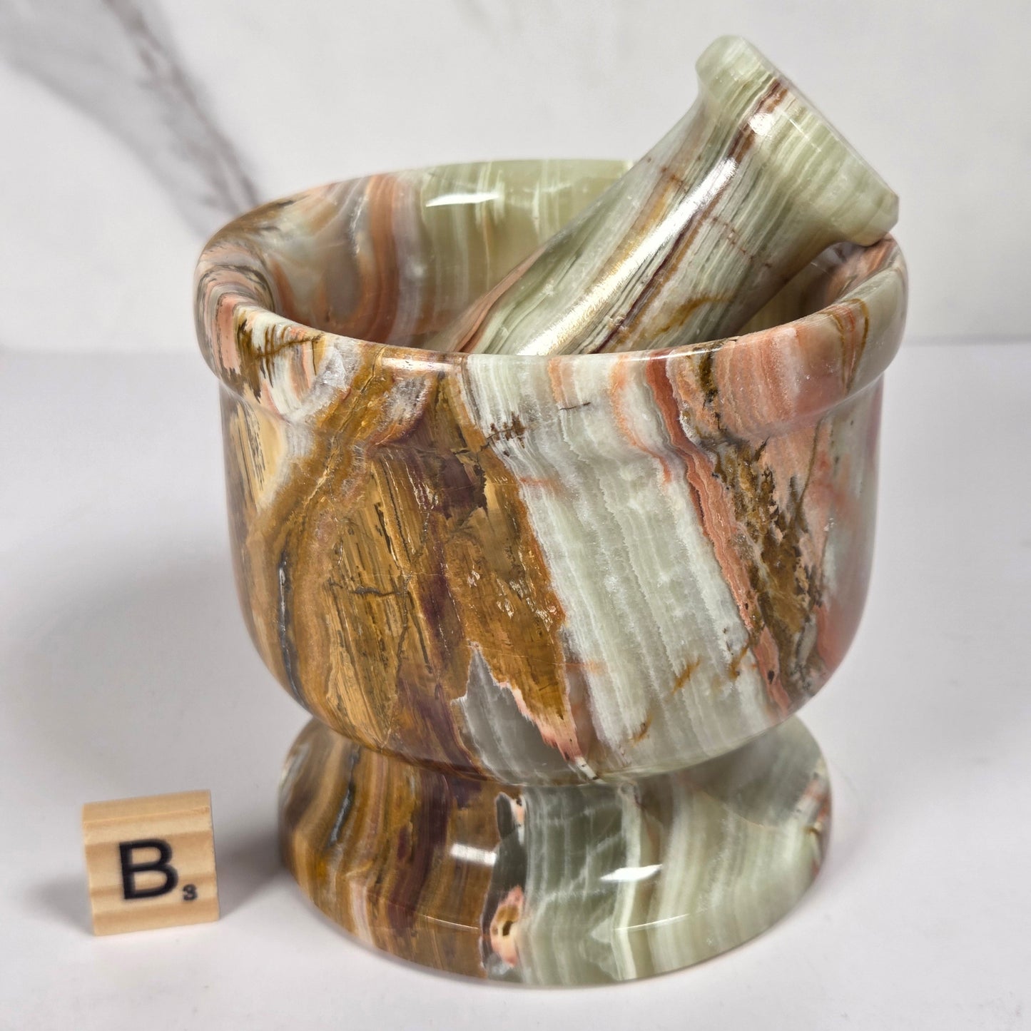 Afghan Onyx pestle and mortar set on a white surface with a gray background