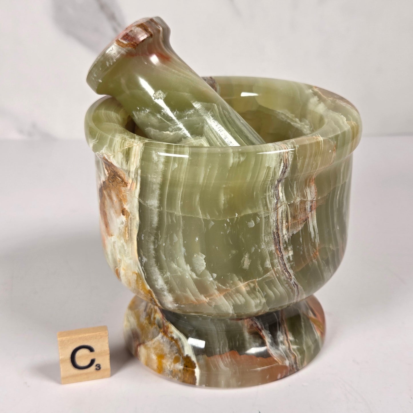 Afghan Onyx pestle and mortar set on a white surface with a gray background