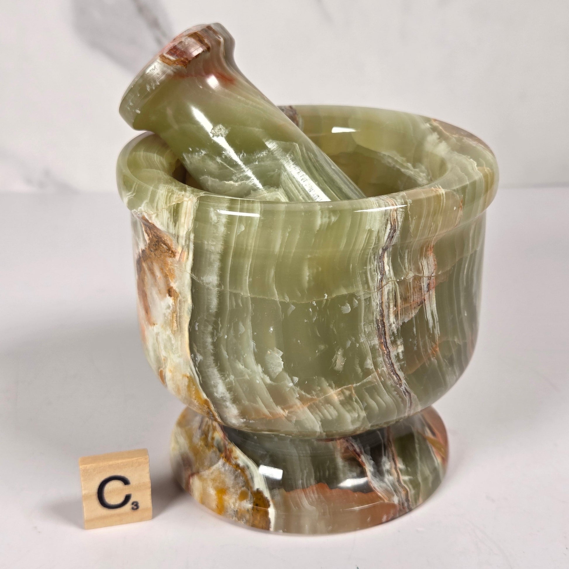 Afghan Onyx pestle and mortar set on a white surface with a gray background