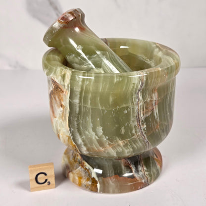Afghan Onyx pestle and mortar set on a white surface with a gray background