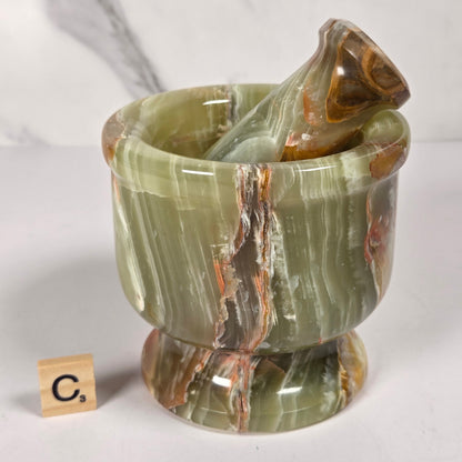 Afghan Onyx pestle and mortar set on a white surface with a gray background