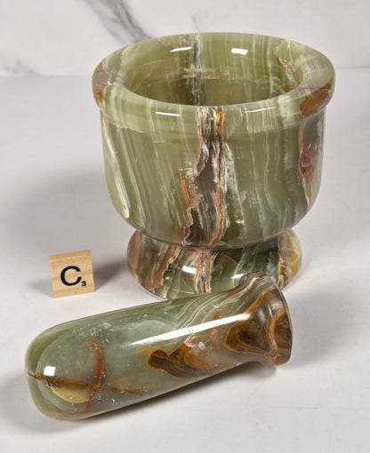 Afghan Onyx pestle and mortar set on a white surface with a gray background