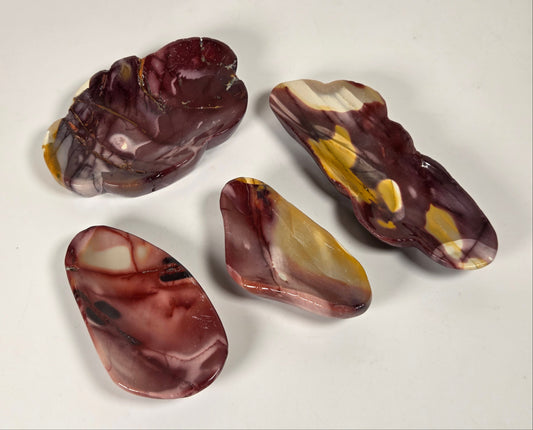 Four polished agate stone pieces with marbled patterns of burgundy, brown, cream, and yellow on a plain white background.