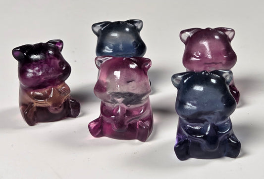 small translucent bear-shaped figurines in shades of purple, blue, and pink, arranged on a plain light background.